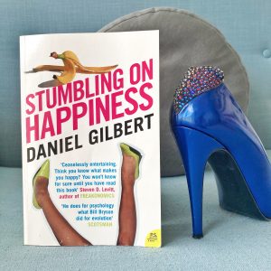 picture of the cover of stumbling on happiness next to a blue shoe with rhinestones